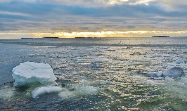 Järvimaisema, jossa jäälauttoja ja auringonlasku.