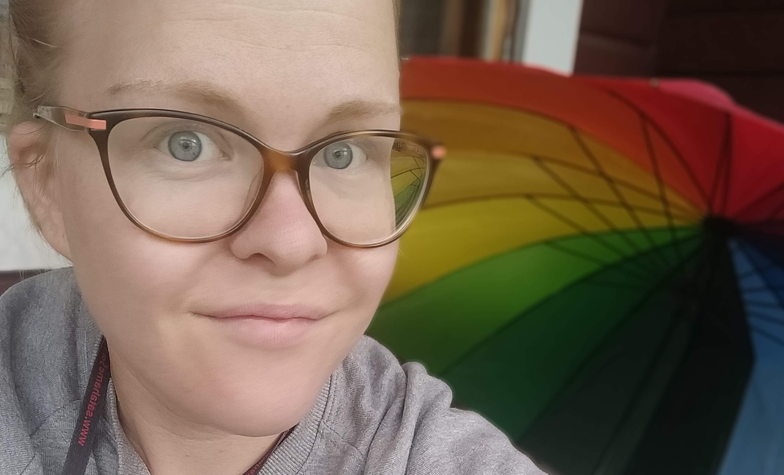Vaaleahiuksinen, hymyilevä Aletta Palosaari. Taustalla värikäs sateenvarjo.