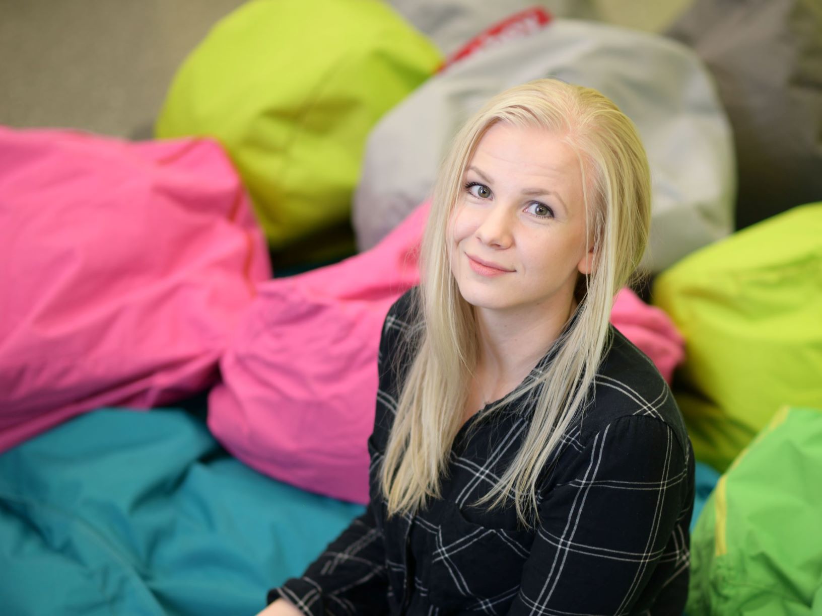 Vaaleahiuksinen, hymyilevä Johanna Flinkman. Taustalla värikkäitä Fatboy-tyynyjä.